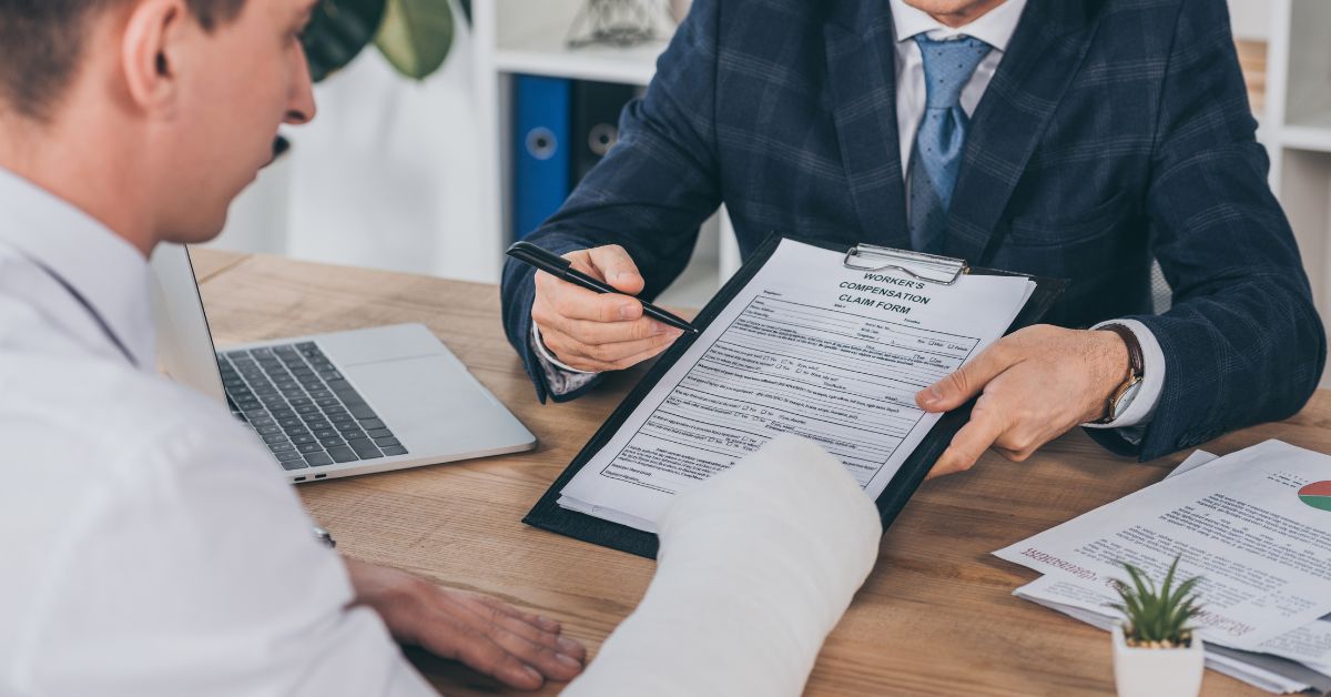 man with broken arm looking over forms with workers' comp. attorney